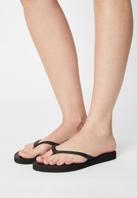 Zwarte teenslippers met een gereedschapsrubberen band en een vlakke zool. Minimalistisch ontwerp met een eenvoudige teenpost voor een veilige pasvorm.