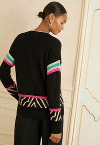 Melna džemperis ar krāsainiem svītru akcentiem tirkīza, rozā un krējuma krāsā; apakšmalā ir zebras raksts; mīksta tekstūra, garas piedurknes.