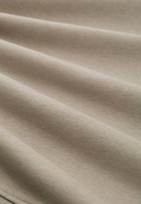 Beige színű pamutanyag, mely puha tapintású, sima, folyó redőkkel és egységes, egyenletes felülettel rendelkezik. A finom csillogás fokozza a megjelenést.