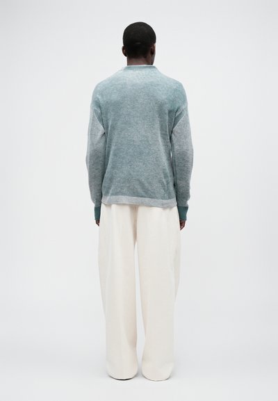 Hele sinine dress shirt tekstuuriga viimistlusega, millel on ümar kaelus ja soonikkoes mansetid, kombineeritud lahtiste valgete pükstega.