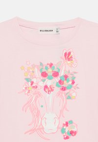 Ροζ βαμβακερό μπλουζάκι με γραφικό ενός μονόκερου διακοσμημένο με πολύχρωμες παγιέτες και λουλουδένια σχέδια σε αποχρώσεις του ροζ, πράσινου και κίτρινου.