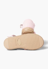 Sandal in tessuto rosa con suola in juta intrecciata, cinturino regolabile e suola in gomma testurizzata. L'etichetta riporta "FABBRICATO IN SPAGNA."