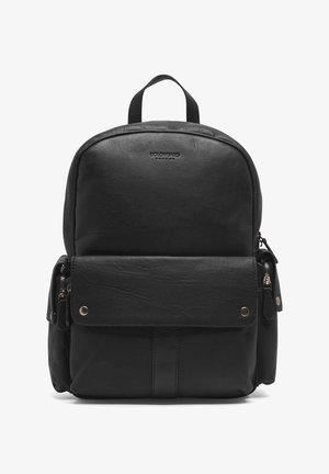 Zwarte leren rugzak met ronde hoeken, een voorflapzak en een ritszak aan de zijkant. Voorzien van goudkleurige hardware en gestikte accenten.