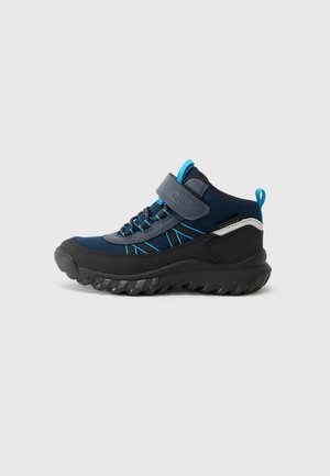 Chaussure de sport bleue marine et noire pour enfants, avec des accents bleus, une bride auto-agrippante, des lacets élastiques et une semelle extérieure texturée pour une meilleure adhérence.