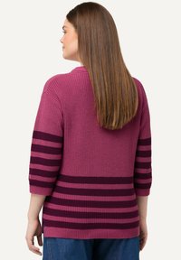 Sweter z dzianiny w odcieniach różu z czarnymi poziomymi paskami, charakczący się luźnym krojem i rękawami o długości trzy czwarte. Teksturowany materiał z prążkowanym dołem.