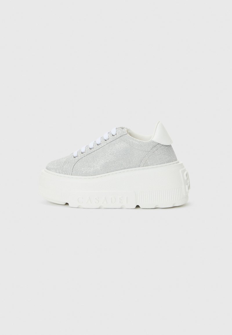Silver sneakers featuring a textured upper, white laces, and a thick, white rubber sole with embossed branding.