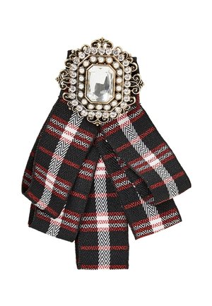 Nœud en tissu à carreaux noir, rouge et blanc avec une broche en or ornée présentant une grande pierre claire et de petites perles au centre.
