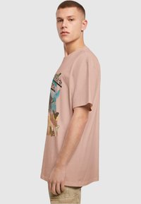 Lyserød bomulds t-shirt med korte ærmer, der har et farverigt sommerfuglegrafik på forsiden. Løs pasform, rund halsudskæring, standard syning.