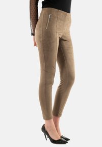 Pantalones marrones, de aspecto ante, con una cintura alta y detalle de cremallera lateral, que presentan un diseño ajustado y una forma de pierna cónica.