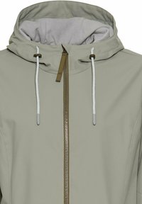 Lichtgrijze hoodiejas met een rits aan de voorkant, contrasterende rits, koordjes en een zachte voering in de capuchon. Glad oppervlak, geen patronen.