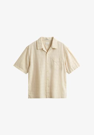 Camicia beige a maniche corte con bottoni, colletto e taschino sul petto, caratterizzata da un delicato motivo a quadretti sfumato.
