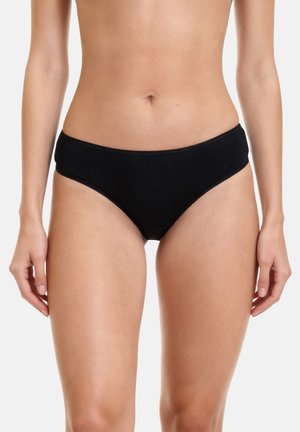 Kvinde iført enkelt sort bikiniunderdel, vist fra midt på torsoen til øvre lår mod en hvid baggrund.