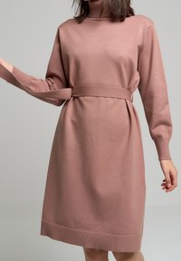 Robe mi-longue à manches longues en tissu tricoté rose poudré, avec ceinture assortie à la taille et poignets et ourlet côtelés.