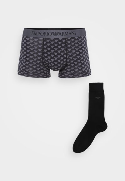 Boxer-shorts noirs en coton avec un motif logo gris et une taille élastique, associés à une chaussette noire unie présentant un petit logo.