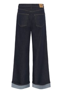 Σκούρο μπλε τζιν παντελόνι με φαρδιά πόδια και γυρισμένα ρεβέρ, δύο πίσω τσέπες και δερμάτινο σήμα της μάρκας στη μέση.