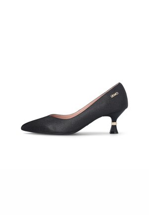Zapato de salón de tela negra con punta puntiaguda, tacón corto acampanado y logo de la marca en dorado en el lateral.