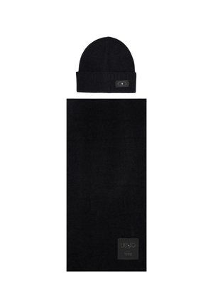 Berretto di maglia nera con risvolto e un piccolo etichetta, abbinato a una sciarpa nera coordinata con un design testurizzato e patch con logo.