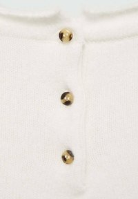 Maglione bianco lavorato a maglia con tre bottoni trasparenti all'collo, dal tocco morbido e una finitura leggermente pelosa.