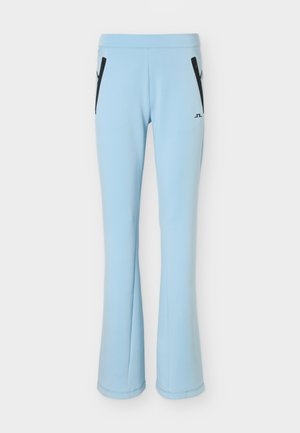 Svetlomodré elastické nohavice s rozšírenými nohavicami, predné čierne vrecká na zips a malým čiernym logom na pravej stehnovej časti.