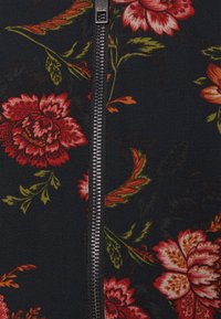 Tissu noir avec un motif floral rouge et orange mettant en valeur une fermeture éclair centrale argentée. Texture douce avec des détails floraux complexes et des accents verts.