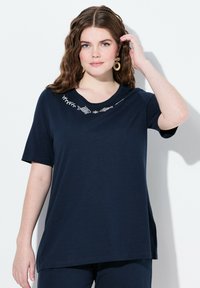 Námořnicky modré tričko s krátkým rukávem, širokým kulatým výstřihem a bílou vyšívanou květinovou výšivkou kolem výstřihu, volný střih.