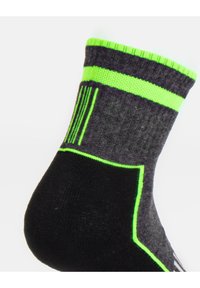Calzini grigi e neri con accenti verde neon. Presentano un bordo rigato, strisce e motivi geometrici lungo i lati.