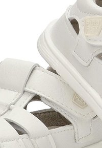 Sandalias blancas de cuero sintético, con múltiples correas, detalles recortados y plantillas texturizadas. Marca visible en el lateral.