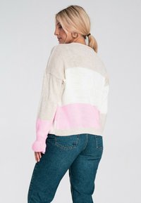 Sweter z teksturowanego dzianiny z poziomymi paskami w odcieniach beżu, bieli i jasnego różu, z ribbowanymi mankietami i dołem. Połączony z spodniami o wysokim stanie.