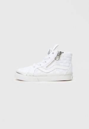 Λευκό ψηλό αθλητικό παπούτσι με καπιτονέ ύφασμα, ασημένια λεπτομέρεια με φερμουάρ, ενισχυμένο κάλυμμα δαχτύλου, επίπεδη λευκή σόλα και κορδόνια μπροστά.