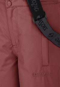 Pantaloni bordeaux con una texture liscia, caratterizzati da un logo a zigzag, tasche laterali e una tracolla nera regolabile.