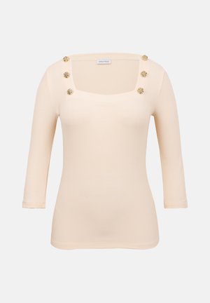 Kreemikas varjundiga soonikkoes kudum, kolmveerandvarrukatega, ja kuus dekoratiivset kuldset nööpi ruudukujulise kaeluse ääres.