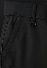 Close-up of black pants pocket with a belt loop featuring a small metal D-ring on the waistband.
