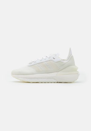 Baskets basses blanches Adidas avec bandes latérales texturées, détail lacets et semelle épaisse rembourrée, vues de côté sur fond blanc.