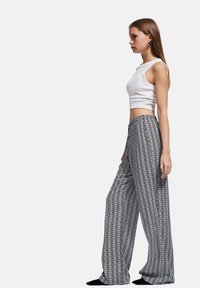 Zwart-witte, met een patroon bedrukte wijde broek met een losse pasvorm, gemaakt van lichtgewicht stof, met een elastische tailleband en abstract ontwerp.