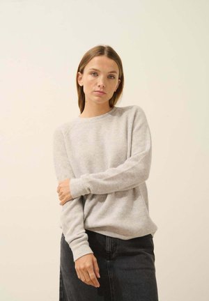 Pull gris clair à côtes avec des manches longues et un col rond, associé à une jupe en denim noir. Design simple et décontracté, avec une texture douce.