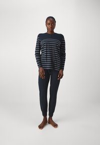 Marinblå randig långärmad topp med rundad halsringning och knapprad, ihopparad med matchande figurnära joggers med elastiska manschetter.