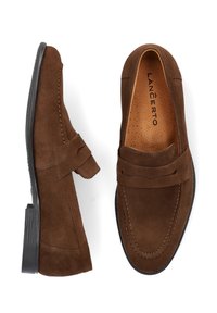 Brązowe zamszowe mokasyny o gładkiej fakturze, zaokrąglonym nosku i dekoracyjnym pasku. Posiadają przeszywane wzory oraz czarną gumową podeszwę.
