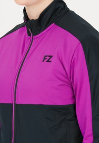 Lila och svart zip-up jacka med hög krage, med FZ-logotyp i svart; mjuk textur; färgblockdesign med kontrasterande paneler.