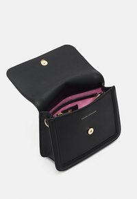 Svart läderhandväska med en strukturerad design, guldfärgad hårdvara, ett enda magnetstängning och en rosa innerfoder med fickor.