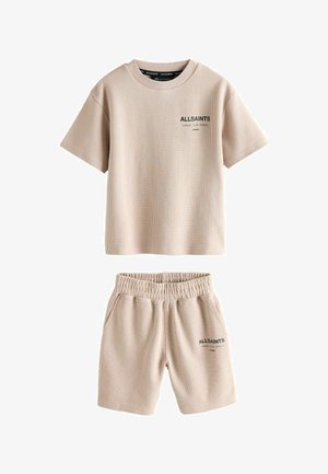 Bézs színű bordázott rövid ujjú póló és hozzáillő, elasztikus derékpántú rövidnadrág, melyeken "ALLSAINTS" logó és japán szöveg található a mellkason és a combon.