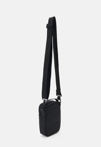 Schwarze Umhängetasche mit strukturiertem Design, verstellbarem Tragegurt und strukturiertem Frontpanel. Aus strapazierfähigem Material gefertigt, mit praktischem Reißverschluss oben.