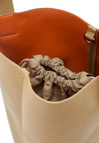 Borsa tote beige realizzata in pelle testurizzata, con un interno arancione a contrasto. Include una pochette in tessuto beige con coulisse all'interno.