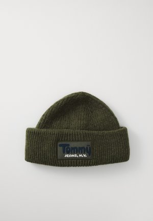 Dark green ribbed knit beanie with folded brim and rectangular patch labeled "Tommy Jeans, N.Y." on a white background.