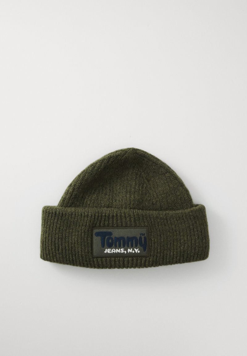Dark green ribbed knit beanie with folded brim and rectangular patch labeled "Tommy Jeans, N.Y." on a white background.