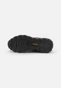 Black rubber outsole with deep tread patterns, featuring the Goodyear logo, designed for traction and durability in outdoor environments.
