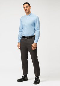 Himmelblaues Langarmhemd mit Mandarinkragen, kombiniert mit dunkelgrauen Hosen und schwarzen Schuhen, im slim fit Design.