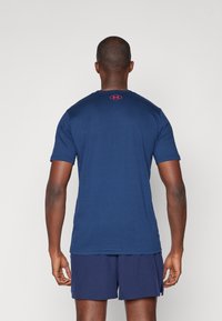 Marineblå kortærmet t-shirt med rund hals, der har et lille rødt logo på ryggen. Blødt stof med en glat overflade.