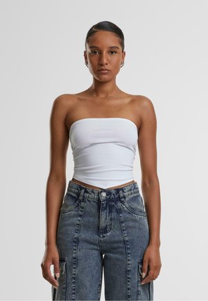 Top bianco senza spalline abbinato a jeans in denim a vita alta con lavaggio scuro, vestibilità affusolata e tasche anteriori con cuciture visibili.