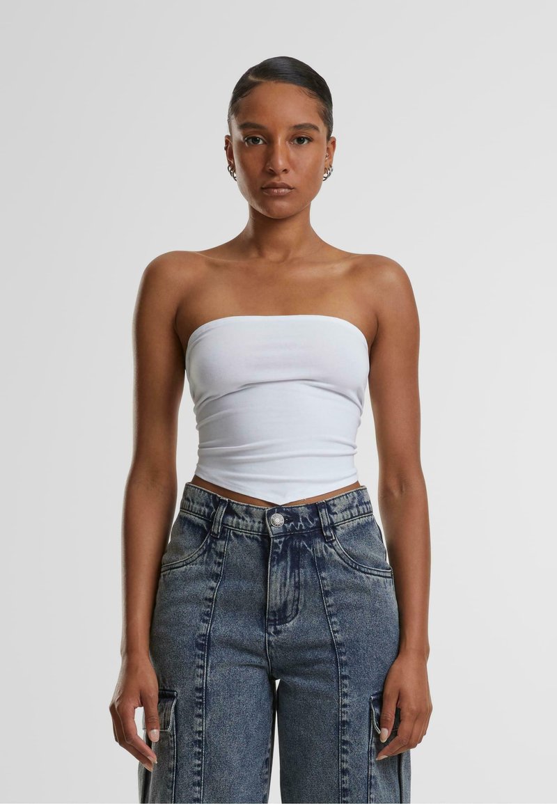 Weißes trägerloses Oberteil kombiniert mit hochtaillierten Jeans aus Denim in dunkler Waschung, schmaler Passform und vorderen Taschen mit sichtbaren Nähten.