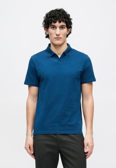 Zils īsām piedurknēm polokrūze ar klasisku apkakli, izgatavota no mīksta kokvilnas auduma. Raksturo tīrs, vienkāršs dizains bez rakstiem.